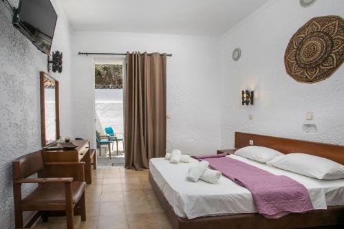 a bedroom with a bed and a desk and a window at CASA MIKELE by Sarikas Anthony Quinn Beach Faliraki - Ladikos Garden in Faliraki