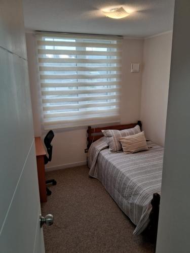 a bedroom with a bed in front of a window at Departamentos Pilmaiquen in Padre Las Casas