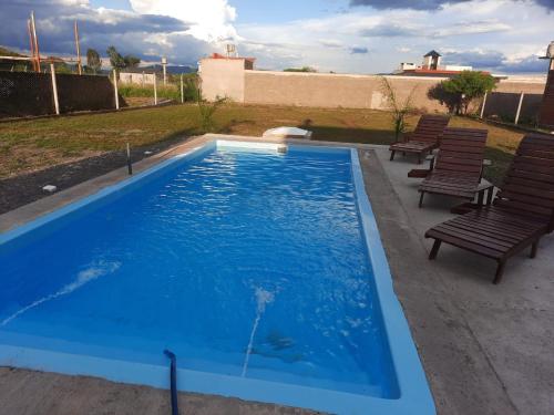 uma grande piscina azul com bancos e cadeiras em Casa de Campo en Salta em Salta