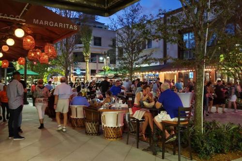 a group of people sitting at tables on a city street at Whole House+Renovated+Pool+Lanai+BBQ+Close to All in West Palm Beach