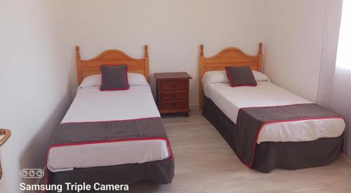 casa rural el mirador في Granja Arenales: غرفة نوم بسريرين وخزانة خشبية