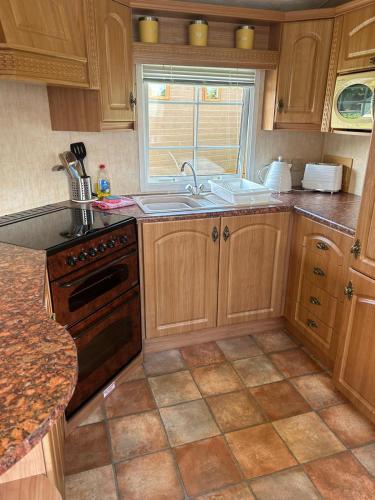 a kitchen with wooden cabinets and a sink and a stove at Stunning Caravan Whithorn3 in Newton Stewart