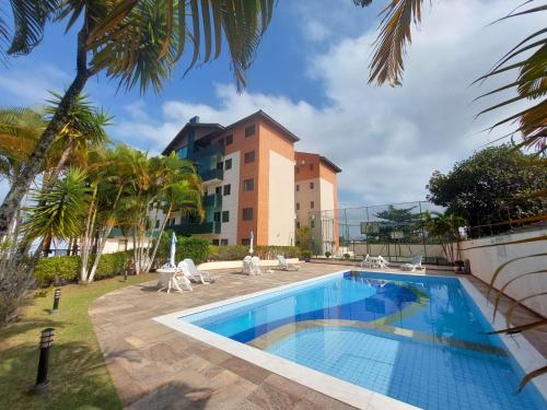 a pool in front of a building with a resort at Apartamento Peruíbe in Peruíbe