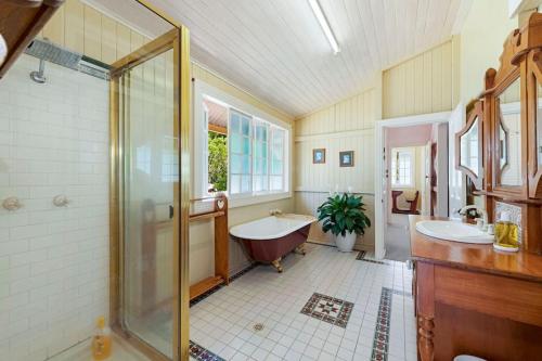 W łazience znajduje się wanna, umywalka i prysznic. w obiekcie A Charming Queenslander w mieście Bundaberg