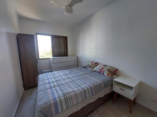 Habitación pequeña con cama y ventana en Apartamento Peruíbe, en Peruíbe