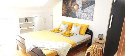 um pequeno quarto com uma cama com almofadas amarelas em Apartman Blagojevic Hill em Arandjelovac