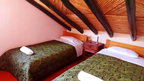 1 Schlafzimmer mit 2 Betten und Holzdecke in der Unterkunft Cabaña la Cattleya de Villa de Leyva in Villa de Leyva