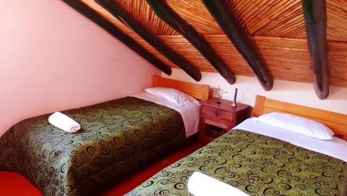 Un dormitorio con dos camas y techo de madera. en Cabaña la Cattleya de Villa de Leyva, en Villa de Leyva