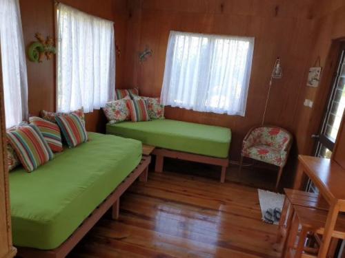 a room with two green couches in a house at Nabuco Estate Bure Rentals in Naweni