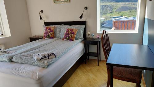 a bedroom with a bed and a table and a window at Olafsvik Guesthouse in Ólafsvík