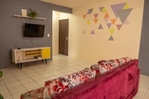 a living room with a red couch and a tv at Apartamento a 50m da praia da Enseada. in São Francisco do Sul