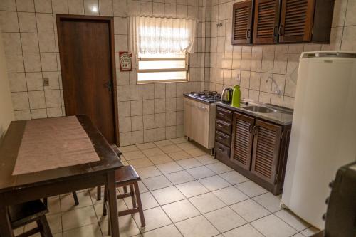 a kitchen with a refrigerator and a table in it at Apartamento a 50m da praia da Enseada. in São Francisco do Sul