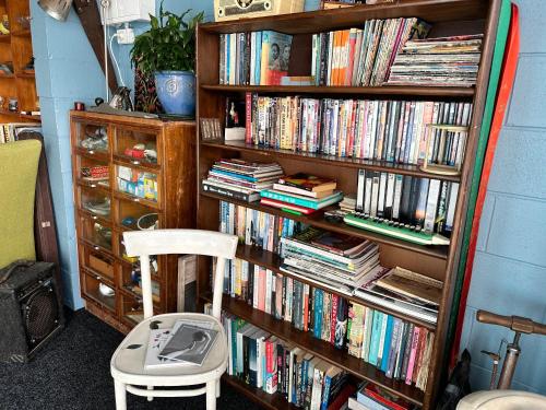 uma estante cheia de livros ao lado de uma cadeira em The SeaHouse em Kerikeri