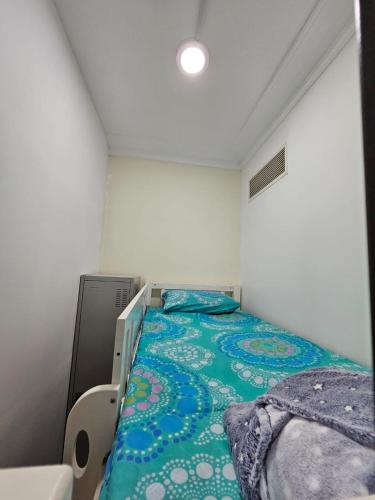 a small bedroom with a bed with a green blanket at SKY 9 Hostel in Dubai