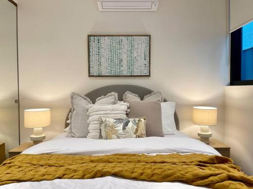 een slaapkamer met een bed met kussens en 2 lampen bij Modern 2 Bedrooms FREE Carpark in Melbourne