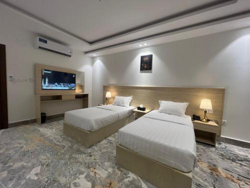 Cette chambre comprend 2 lits et une télévision à écran plat. dans l'établissement سويت إم للأجنحة الفندقية, à AR Rummanah