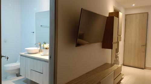 a bathroom with a toilet and a television on the wall at Hotel Kai in Uribia