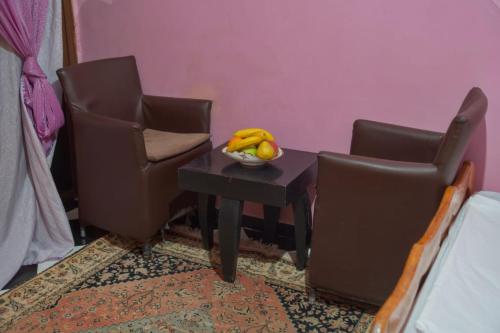 a table with two chairs and a bowl of fruit on it at Riad Dar Fadma in Ouarzazate