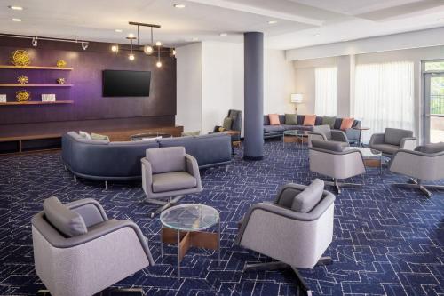 a waiting room with couches and chairs and a tv at Courtyard by Marriott Charleston Downtown/Civic Center in Charleston
