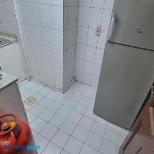 a kitchen with a refrigerator and a tiled floor at Dormitory bed space in a shared room in Sharjah