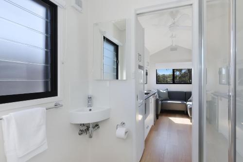 a white bathroom with a sink and a mirror at Reflections Ferry Reserve - Holiday Park in Brunswick Heads