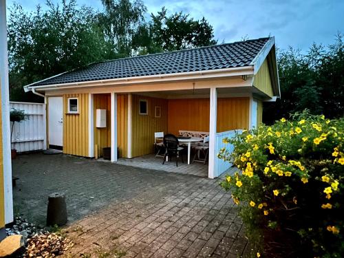 Casa amarilla pequeña con mesa y patio en Harekaergaardsvej en Kirke-Hyllinge