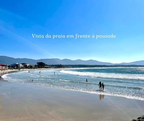 two people walking in the water on a beach at Pousada Hoffmann in Florianópolis