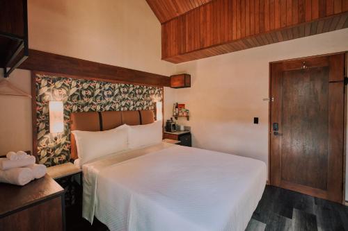 a bedroom with a white bed and a wooden door at Suwa Villa Arenal in Fortuna