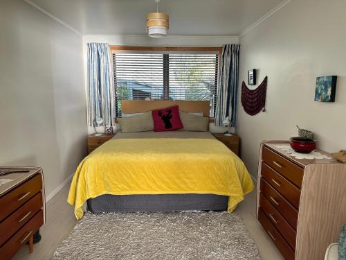 a bedroom with a yellow bed and a window at The SeaHouse in Kerikeri