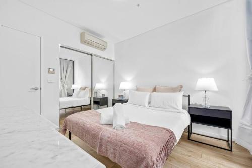 a white bedroom with a large bed and a desk at Convenient Modern 2Bed Apt Near Airport in Sydney
