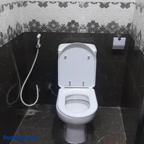 a bathroom with a white toilet in a black wall at Making friends with guests in Sharjah