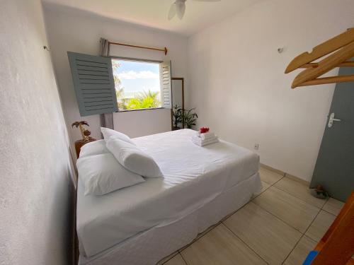 a white bed in a room with a window at Casa Praia a Beira Mar Guriú Ceará in Guriú