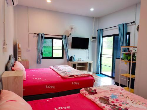 una camera con due letti e una tv di Pimpisa Garden a Ban Khuang Kom