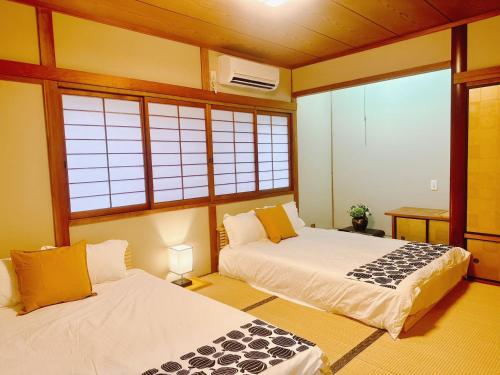 two beds in a room with windows at Retreat Tengachaya 旅趣 天下茶屋 in Osaka