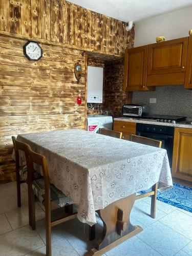 a kitchen with a table and a clock on the wall at Casa vacanze la torre in Malonno