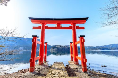 an orange torii gate on a body of water at Oku Yugawara SANSUIROU in Yugawara