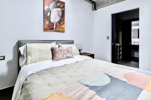 a bedroom with a large bed with a painting on the wall at Encanto Cayala, Apartamento moderno a minutos caminando de Embajada USA y Paseo Cayala in Guatemala