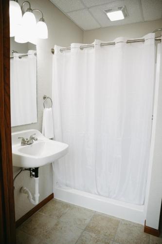 a bathroom with a white shower curtain and a sink at Bricktown Inn in Camp Point