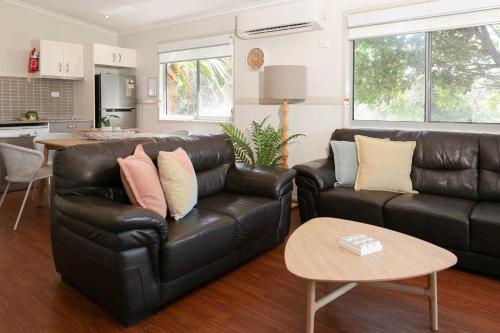 a living room with a leather couch and a table at Reflections Lennox Head - Holiday Park in Lennox Head