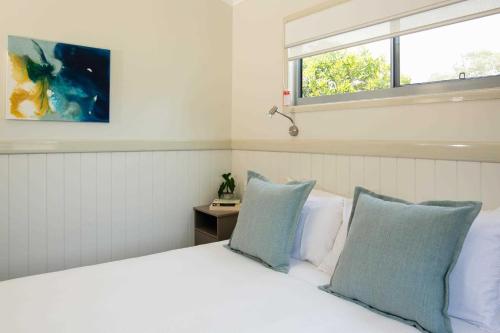 a bedroom with a white bed with blue pillows at Reflections Lennox Head - Holiday Park in Lennox Head