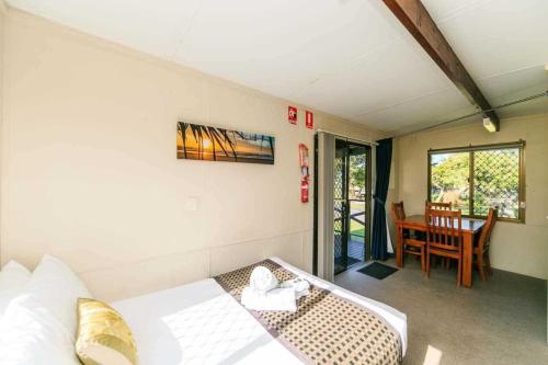 Habitación con cama y comedor con mesa. en Reflections Lennox Head - Holiday Park, en Lennox Head