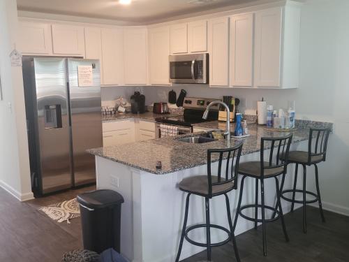 a kitchen with white cabinets and a counter with bar stools at SC 3755 New 2 bedroom Townhouse Ft Jackson & USC in Columbia