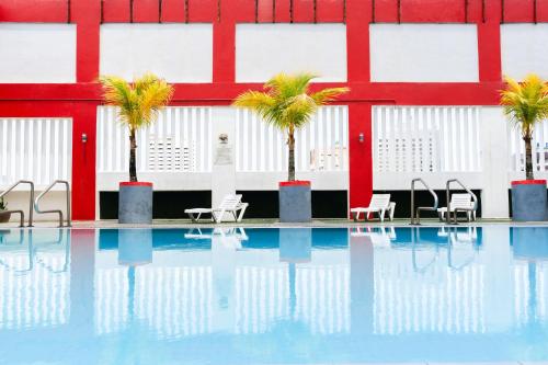 a pool with chairs and palm trees in front of a building at Hotel Sentral Melaka @ City Centre in Malacca