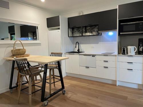 a kitchen with white cabinets and a table and chairs at Il Palazzo Holiday Apartments in Cairns