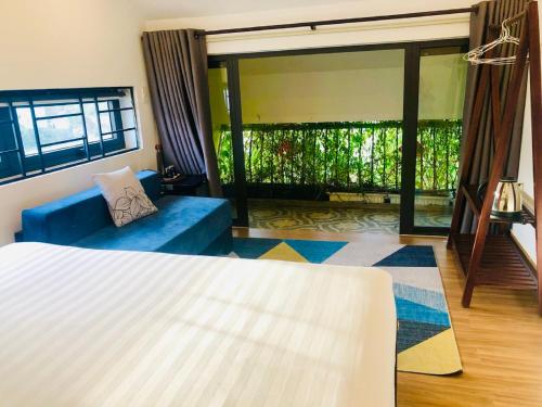 a living room with a bed and a blue couch at PHỐ CHỢ ĐÊM Villa - Near Hoi An Old Town 200m in Hoi An