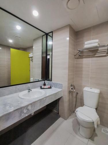 a bathroom with a sink and a toilet and a mirror at Hotel Sentral Melaka @ City Centre in Melaka