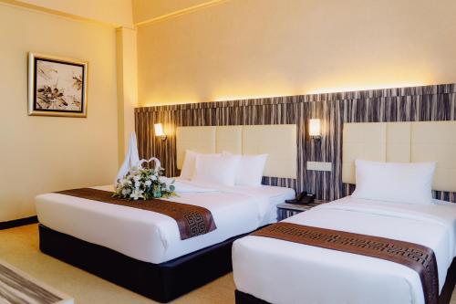 a hotel room with two beds with flowers on them at Hotel Sentral Melaka @ City Centre in Melaka