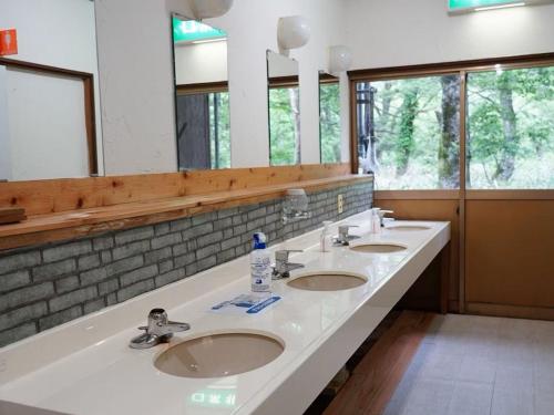 a bathroom with three sinks and a large mirror at Yamano Hidaya in Matsumoto
