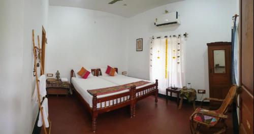 a bedroom with a bed with white sheets and a window at Tranquility Guest House in Srīrangam