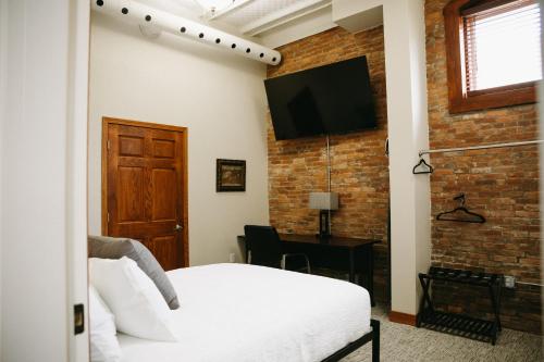 a bedroom with a white bed and a brick wall at Bricktown Inn in Camp Point